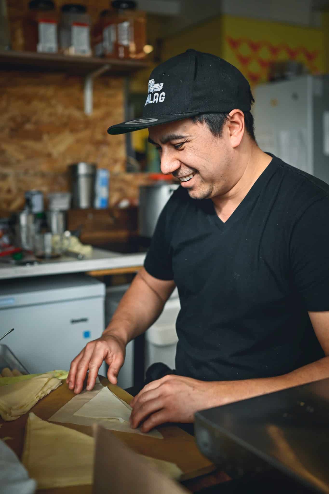 Chef souriant préparant soigneusement un plat dans la cuisine de son restaurant.